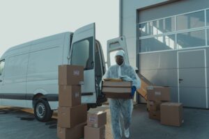 Home A delivery worker in PPE unloads boxes from a van. Efficient and safe logistics.